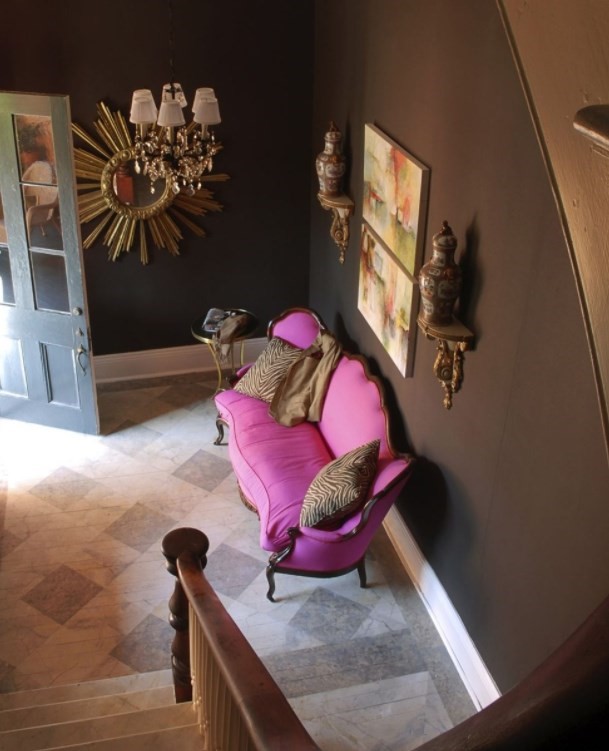 Шоколадно-коричневые стены — довольно необычное решение, но розовый диван отправляет их в нокаут. Идеально вписывается в облик холла клетчатый «плед» мраморного пола.