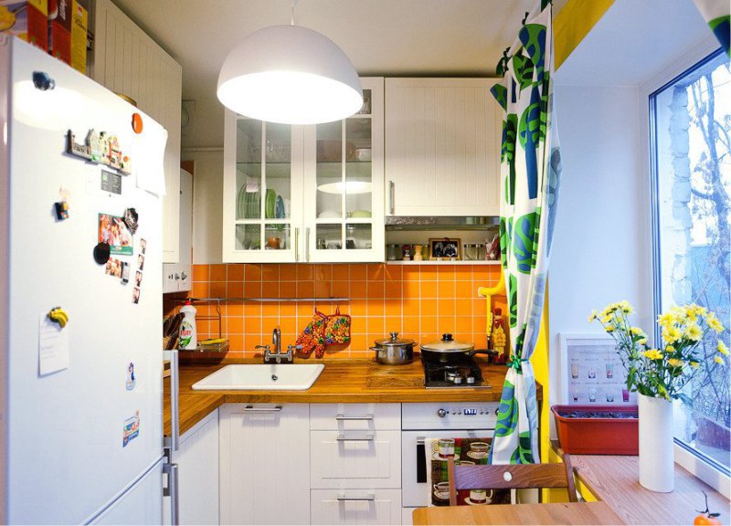Ваза с желтыми цветами на подоконнике кухни в хрущевке