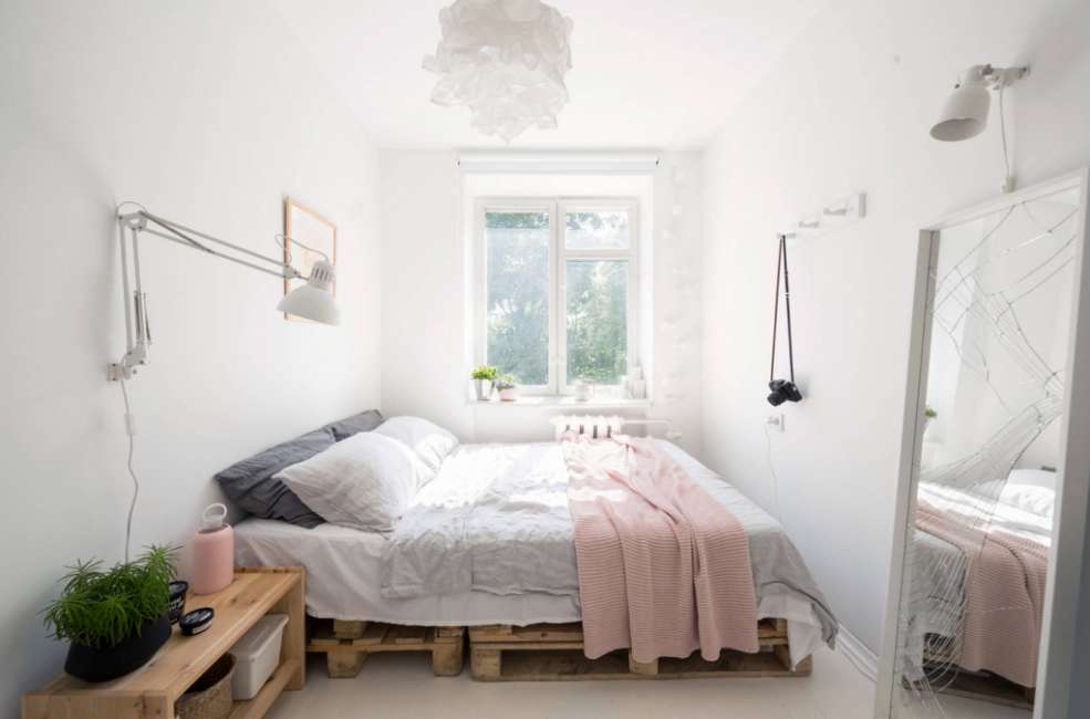 В спальне — просторная кровать, которая стоит на деревянных поддонах